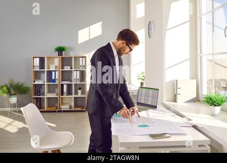 Professioneller Kartograf, der an seinem Arbeitsplatz mit einer gedruckten Katasterkarte arbeitet. Stockfoto