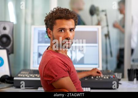 Porträt, Musik und ein Mann Produzent in einem Aufnahmestudio, der Audio mit einem Soundpult mischt. Computer, Technik oder Medien mit einem ernsthaften jungen DJ oder Ingenieur Stockfoto