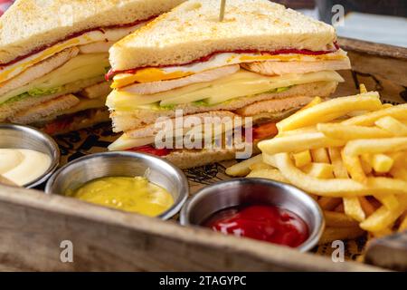 Chicken Club Sandwich mit Pommes, Ketchup, Senf und Mayonnaise Stockfoto