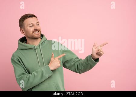 Freundlicher, fröhlicher, unrasierter Mann mittleren Alters, der spielerisch mit den Fingern angenehm lächelt Stockfoto