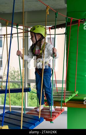 Kinderseilbahn im Spielzimmer passiert das kleine Mädchen die Seilbahn, die aktive und körperliche Entwicklung des Kindes. Stockfoto