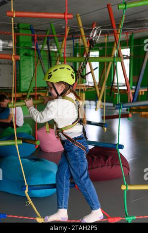 Aktive und körperliche Entwicklung des Kindes, das Mädchen passiert die Seilbahn im Spielzimmer. Stockfoto