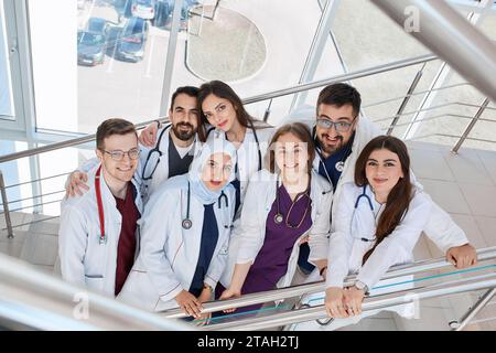 Eine Gruppe fröhlich lächelnder Ärzte im Krankenhausflur. Medizinstudenten verschiedener Rassen in Kapmus Stockfoto