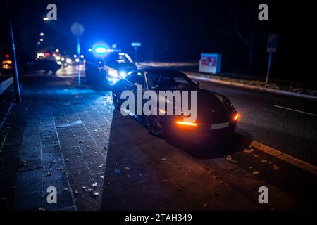 Ein Streifenwagen der Polizei mit eingeschalteten Blaulicht hinter einem Porsche Carrera 911 S4 nach einem Verkehrsunfall mit Bagatellschaden. Stockfoto