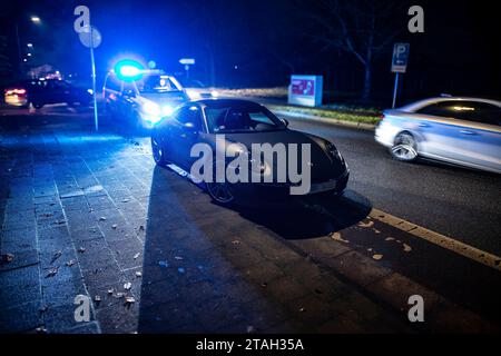 Ein Streifenwagen der Polizei mit eingeschalteten Blaulicht hinter einem Porsche Carrera 911 S4 nach einem Verkehrsunfall mit Bagatellschaden. Stockfoto