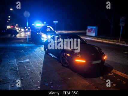 Ein Streifenwagen der Polizei mit eingeschalteten Blaulicht hinter einem Porsche Carrera 911 S4 nach einem Verkehrsunfall mit Bagatellschaden. Stockfoto