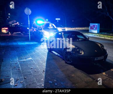 Ein Streifenwagen der Polizei mit eingeschalteten Blaulicht hinter einem Porsche Carrera 911 S4 nach einem Verkehrsunfall mit Bagatellschaden. Stockfoto