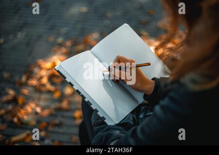 Frau mit Notizblock. Nahaufnahme eines jungen Mädchens, das in ihr Tagebuch schreibt, im Park. Eine Frau schreibt in ein Notizbuch mit einem Stift auf der Straße. Webbanner Stockfoto