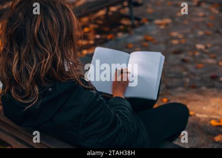 Frau mit Notizblock. Nahaufnahme eines jungen Mädchens, das in ihr Tagebuch schreibt, im Park. Eine Frau schreibt in ein Notizbuch mit einem Stift auf der Straße. Webbanner Stockfoto