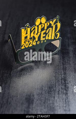 Happy New Year Hintergrund. Schwarze, lustige Papiergläser auf dem schwarzen Tisch. Stockfoto