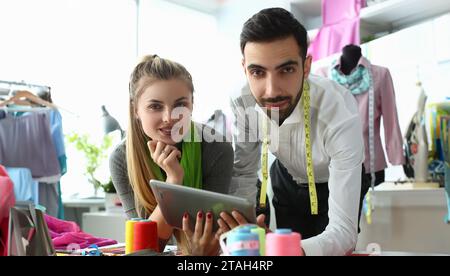 Designer von Männern und Frauen diskutieren in der Werkstatt über neue Kleidungskollektion auf einem digitalen Tablet Stockfoto