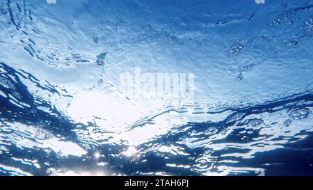 Unterwasserbild der Sonne, die durch Meerwasser schimmert und Luftblasen in klarem Meerwasser. Stockfoto