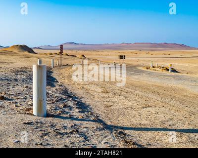 Atemberaubende, mit weißen Pfählen markierte unbefestigte Straße, die durch die Wüste im Paracas National Reserve, Peru, führt Stockfoto