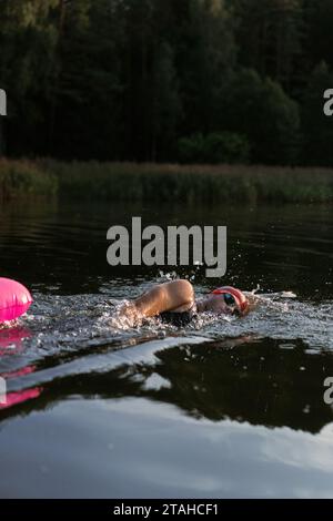 Professioneller Schwimmer in einem Neoprenanzug schwimmt im offenen Wasser auf einem See. Stockfoto