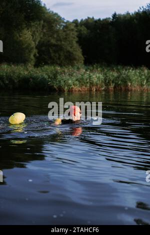 Professioneller Schwimmer in einem Neoprenanzug schwimmt im offenen Wasser auf einem See. Stockfoto