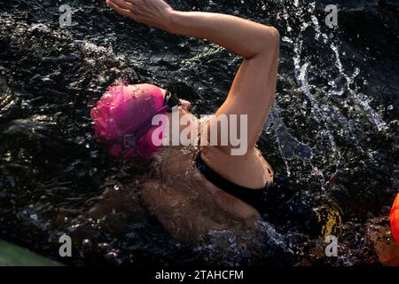 Professioneller Schwimmer in einem Neoprenanzug schwimmt im offenen Wasser auf einem See. Stockfoto