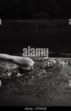 Professioneller Schwimmer in einem Neoprenanzug schwimmt im offenen Wasser auf einem See. Stockfoto