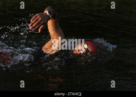 Professioneller Schwimmer in einem Neoprenanzug schwimmt im offenen Wasser auf einem See. Stockfoto