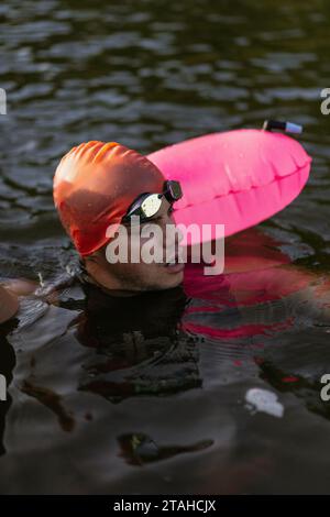 Professioneller Schwimmer in einem Neoprenanzug schwimmt im offenen Wasser auf einem See. Stockfoto