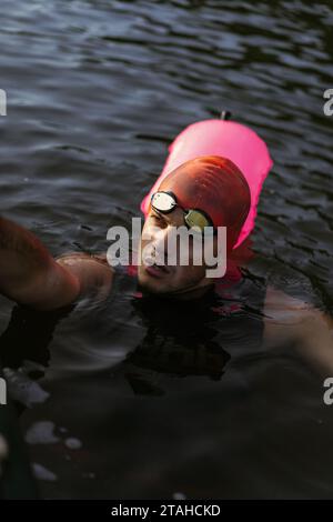 Professioneller Schwimmer in einem Neoprenanzug schwimmt im offenen Wasser auf einem See. Stockfoto