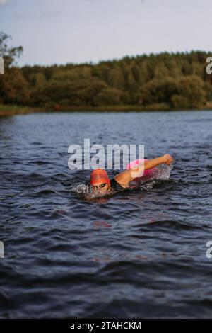Professioneller Schwimmer in einem Neoprenanzug schwimmt im offenen Wasser auf einem See. Stockfoto