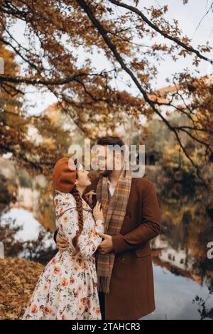 Ein Mann und eine Frau in Mänteln laufen mit einem Date durch einen Herbstpark Stockfoto