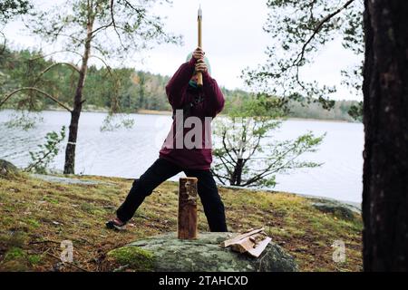 Kind, das Holz mit einer Axt im Wald hackt Stockfoto