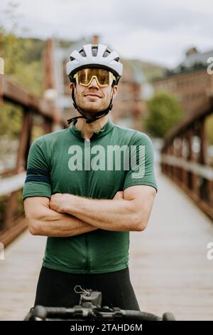 Porträt eines Radfahrers mit überkreuzten Armen und Helm und Brille Stockfoto