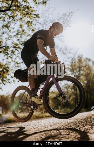 Männlicher Radfahrer auf einem lila Fahrrad macht einen Hasen auf Schotterpiste Stockfoto