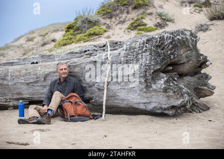 Ein älterer Mann ruht sich gegen einen Log-in Point Reyes National Seashore aus Stockfoto