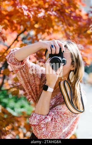 Frau fotografiert im herbstfarbenen Wald mit einer digitalen Spiegelreflexkamera Stockfoto