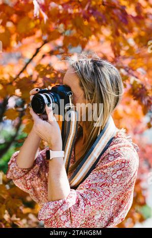 Frau fotografiert mit einer digitalen Spiegelreflexkamera das Herbstlaub Stockfoto
