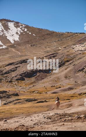 Einheimischer Reiseleiter mit Reittouristen zu Pferd mit traditioneller Kleidung auf Wanderung zum farbenfrohen Regenbogenberg in der Nähe von Cusco, Peru Stockfoto