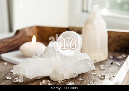 Nummer 16 auf der Edelsteinkugel oder Kristallkugeln, bekannt als Kristallum orbis und Orbuculum. Natürliche klare Quarzkugel auf dem Ständer auf Holzschale zu Hause. P Stockfoto