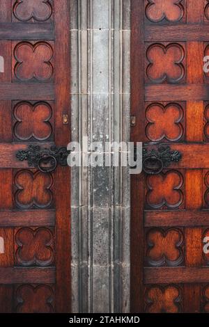 Eine Nahaufnahme einer Holztür mit kunstvoll geschmiedeten Griffen und Messingbeschlägen. Stockfoto