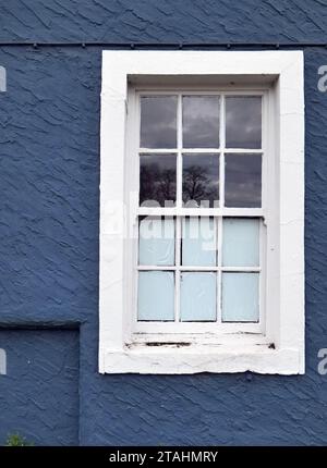 Ferrybridge, UK 11 28 2023 : Ein weißes hölzernes Flügelfenster, das an einer dunkelblau gerenderten Wand befestigt ist. Ein Detail des unverwechselbaren Golden Lion Pubs. Stockfoto