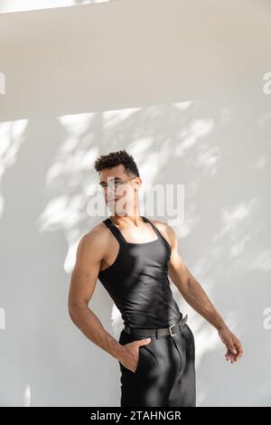 Modischer und gut aussehender junger kubanischer Mann in Sonnenbrille und schwarzem Outfit, der in Miami posiert Stockfoto