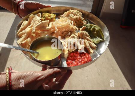 Frau, die Gujarati-Spezialgericht Fafda Jalebi mit Traitional Papaya Chutney hält. Gaanthiya Fafda mit Besan Kadhi serviert auf Thaali Stockfoto