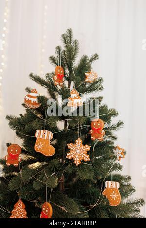 Wunderschöner Weihnachtsbaum dekoriert traditionelle hausgemachte Lebkuchenmänner, Schneeflocken, Stiefel und Kugeln Kekse mit Glasur, Girlanden Lichter, essbare Kugeln Stockfoto