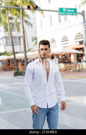 Porträt eines jungen kubanischen Mannes in Jeans und weißem Hemd, der in Miami, South Beach, in die Kamera blickt Stockfoto