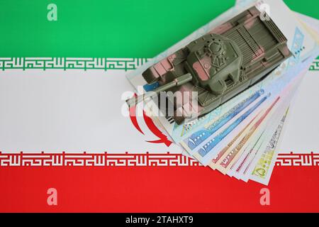 Iranische Armee Spielzeugpanzer-Antrieb auf iranischen Rial-Wechseln auf der Flagge der Islamischen Republik Iran Nahaufnahme Stockfoto