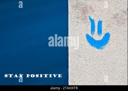 Positives Gefühl und lächelndes Konzept. Blaues Emoji auf dem Gebäude und blauer Hintergrund. Negativer Kopierraum für die Textplatzierung. Bleiben Sie positiv. Stockfoto
