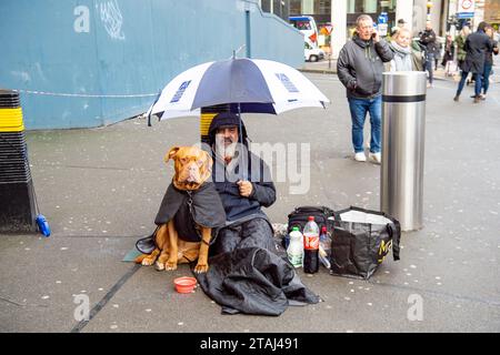 London, Großbritannien. November 2023. Ein Obdachloser sitzt vor der Waterloo Station mit seinem freundlichen Bullen Mastiff Hund. Crisis at Christmas führt ihre jährliche Weihnachtskampagne durch, in der die Menschen aufgefordert werden, Geld zu spenden, um Obdachlosen zu helfen, am Weihnachtstag eine warme Mahlzeit zu essen Stockfoto