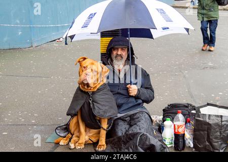 London, Großbritannien. November 2023. Ein Obdachloser sitzt vor der Waterloo Station mit seinem freundlichen Bullen Mastiff Hund. Crisis at Christmas führt ihre jährliche Weihnachtskampagne durch, in der die Menschen aufgefordert werden, Geld zu spenden, um Obdachlosen zu helfen, am Weihnachtstag eine warme Mahlzeit zu essen Stockfoto