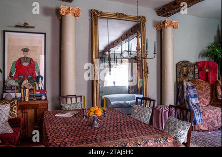 Teppich als Tischdecke mit übergroßem vergoldetem Spiegel in georgianischer Scheune, Tetbury, Gloucestershire, Großbritannien. Stockfoto