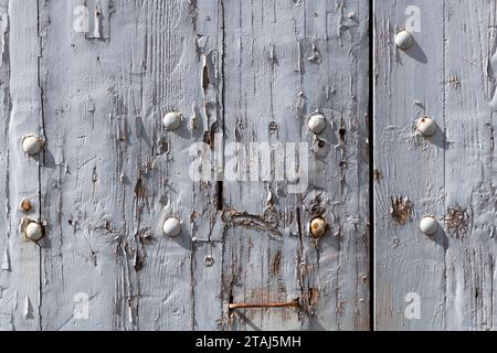 Detail eines Abschnitts eines italienischen Gebäudes mit Holzbrettern mit abblätternder, veralteter, weißer Farbe, Rissen und Beschädigungen. Stockfoto