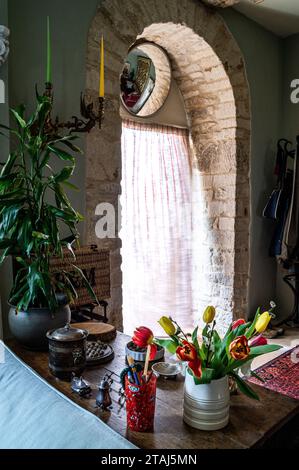 Schneiden Sie Tulpen mit konvexem Spiegel über dem original Cotswold Stein Bogengang in georgianischer Scheune, Tetbury, Gloucestershire, Großbritannien. Stockfoto