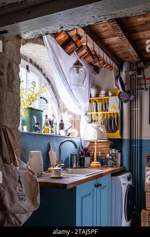 Kupferpfannen über Kücheneinheit mit Waschmaschine in georgianischer Scheune, Tetbury, Gloucestershire, Großbritannien. Stockfoto