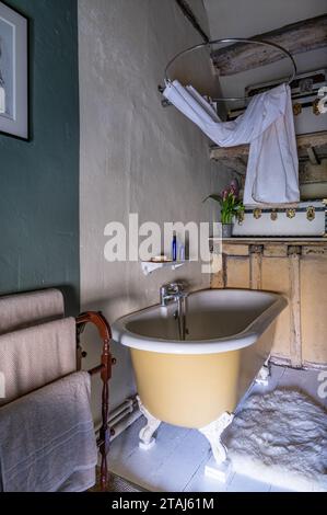 Freistehende Badewanne mit Duschvorhang in georgianischer Scheune, Tetbury, Gloucestershire, Großbritannien. Stockfoto