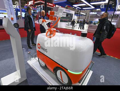 (231201) -- PEKING, 1. Dezember 2023 (Xinhua) -- Besucher schauen sich einen Batterieladeroboter für neue Energiefahrzeuge auf der Sektion Smart Vehicle der China International Supply Chain Expo (CISIE) in Peking, Hauptstadt Chinas, am 1. Dezember 2023 an. Der Bereich Smart Vehicle hat während der CISCE, der weltweit ersten Supply Chain expo auf nationaler Ebene, viele Blicke auf sich gezogen. Mit Schwerpunkt auf der innovativen Entwicklung von Elektrofahrzeugen und intelligenten Fahrzeugen wird in diesem Abschnitt die gesamte industrielle Kette dargestellt und die industrielle Zusammenarbeit, die sektorübergreifende Integration und die gemeinsame Nutzung von Ressourcen gefördert. (Xinhua/Cai Xia Stockfoto